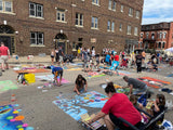 People painting colorful designs on a street in an urban setting.